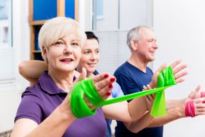 Physio showing senior couple how to use rubber band as expander